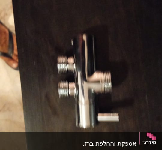 ברז מתכת עם חיבורים מרובים על שולחן כהה